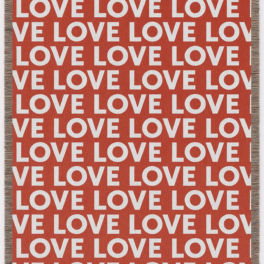 Bold LOVE typography in white on terracotta red cotton woven throw with fringed edges.